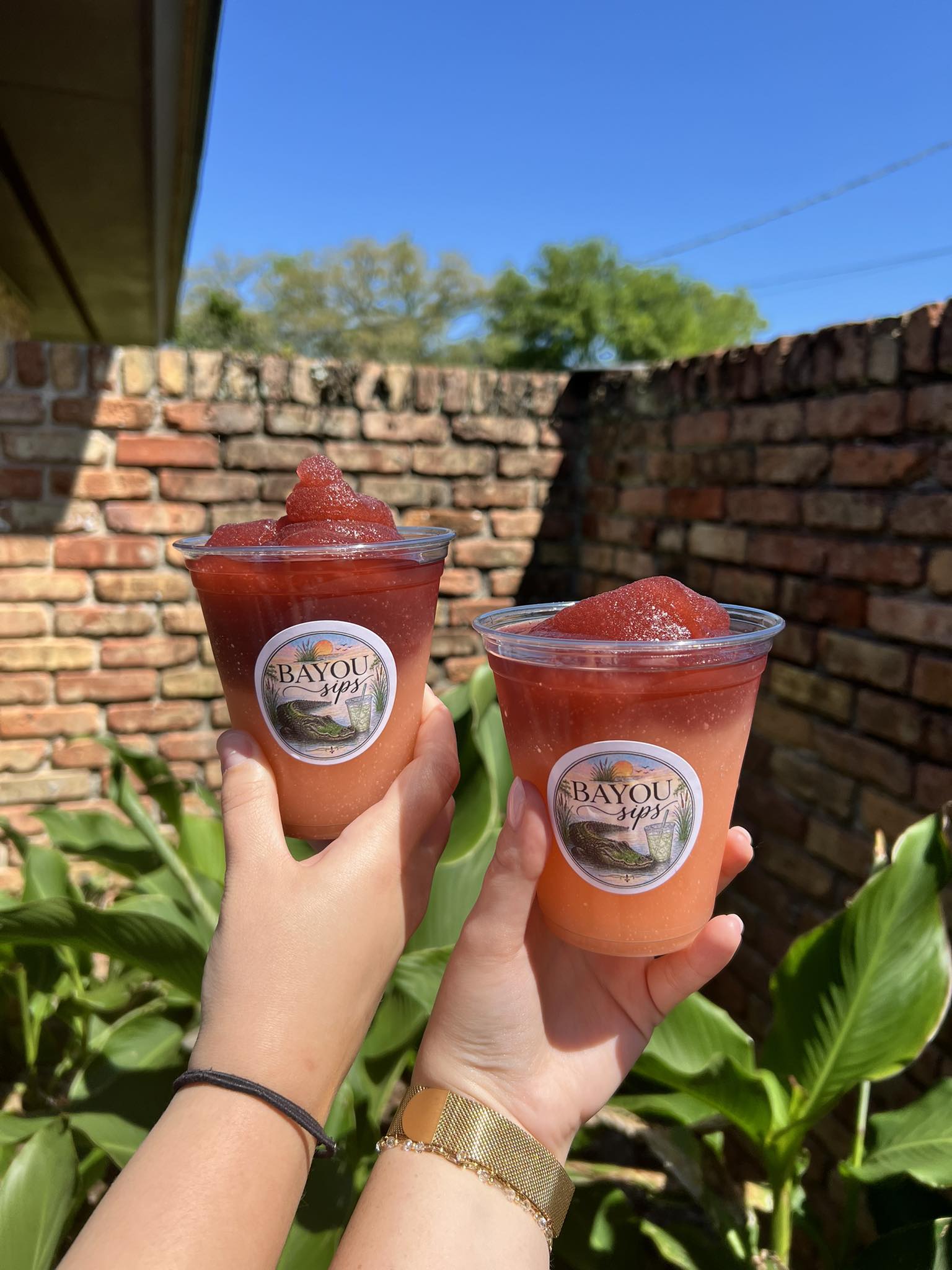 Two strawberry frozen drinks in branded Bayou Sips cups